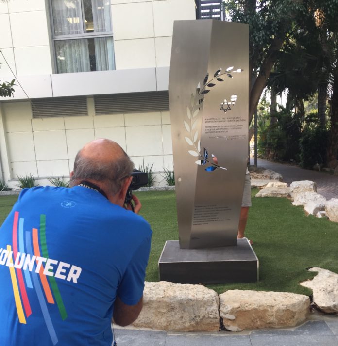 A mártírhalált halt magyar zsidó sportolók emlékművét Maccabiah önkéntes fényképezi, Kfar Maccabiah, Izrael